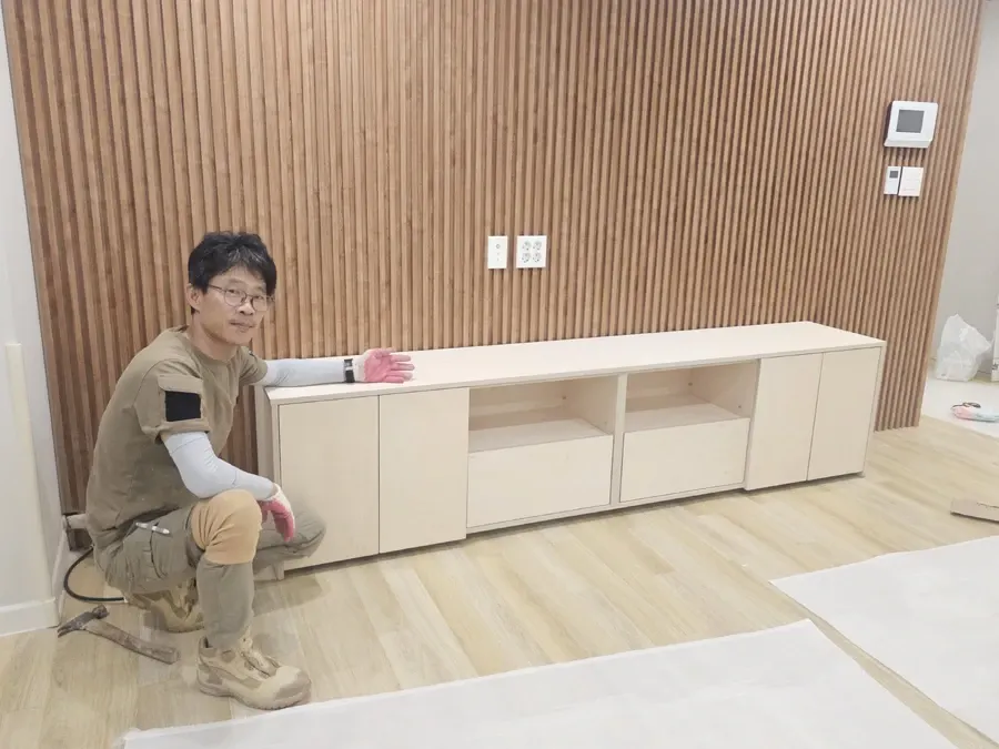 슬랫 벽 앞에 놓인 낮은 TV장 완성 모습 현장 사진